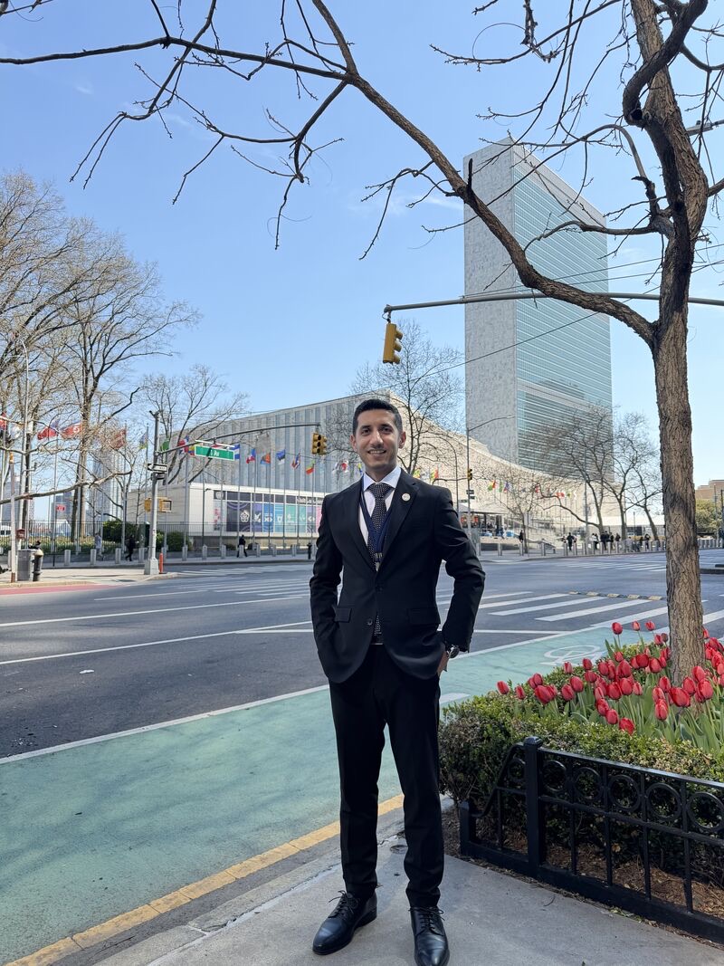 Faizan in a dark suit on First Avenue, with the United Nations Headquarters behind him